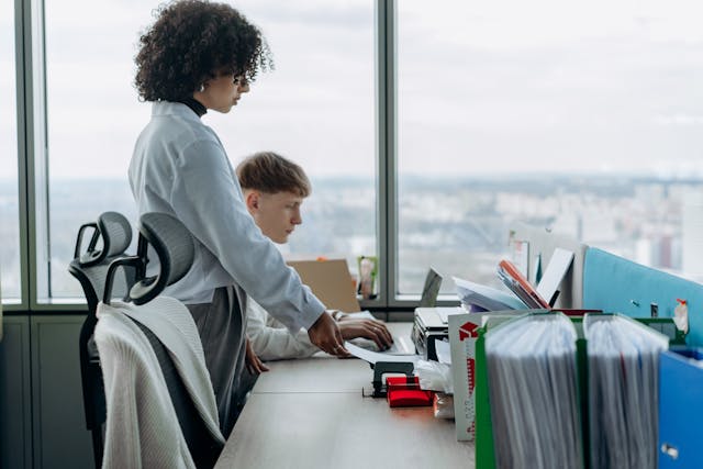 Two young twenty-somethings work side by side in a company.