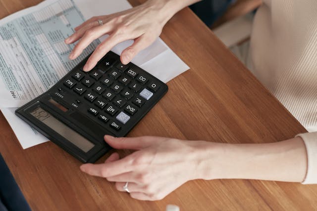 Un femme utilise une calculatrice pour estimer les coûts des recrutements dans son entreprise.
