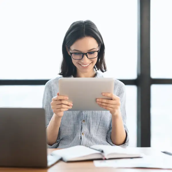 Femme regardant une tablette tactile le sourire aux lèvres