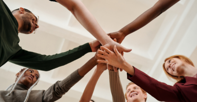 Groupe de personnes superposant leurs mains et faisant preuve de travail d'équipe