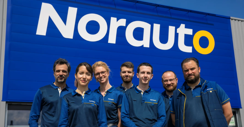 Collaborateurs Norauto devant l'une des enseignes de l'entreprise