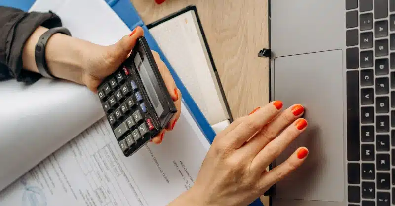 Mains de femme sur son ordinateur qui a une calculatrice